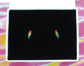 May include: A pair of rainbow lightning bolt stud earrings in a white box with a black interior.