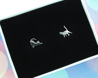 Peut inclure: Une paire de boucles d'oreilles en argent en forme de silhouette de chat. Les boucles d'oreilles sont présentées sur un fond de velours noir dans une boîte blanche.