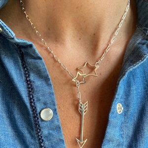 May include: A silver chain necklace with a star charm and an arrow pendant.