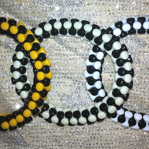 May include: Three beaded bracelets, one black and white, one white and black, and one yellow and black.