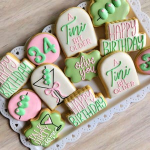 May include: A set of decorated sugar cookies with green and pink frosting. The cookies feature various phrases including "Happy Birthday", "A Tini Bit Older", "Olive You", and "Talk Dirty To Me".