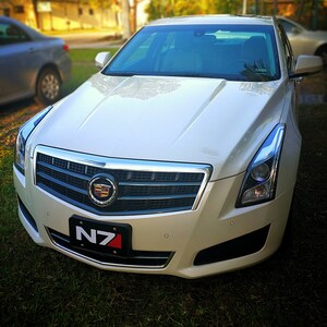 May include: A white Cadillac saloon with a black grille and a number plate that reads "N7".