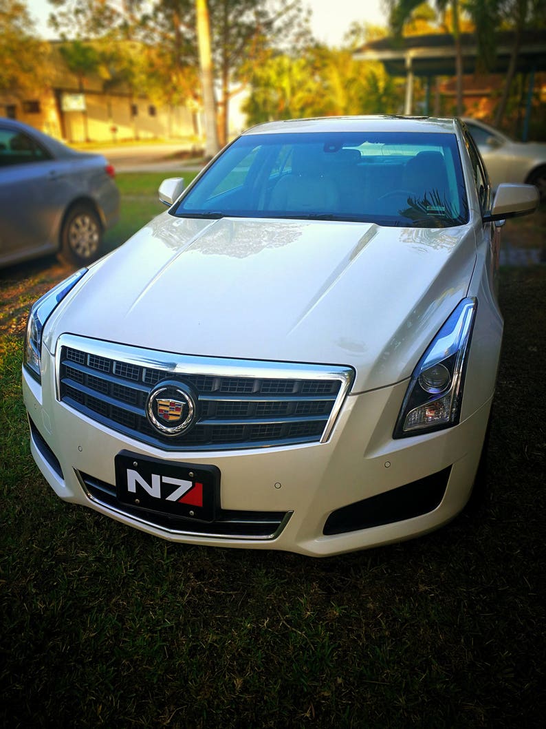 May include: A white Cadillac saloon with a black grille and a number plate that reads "N7".