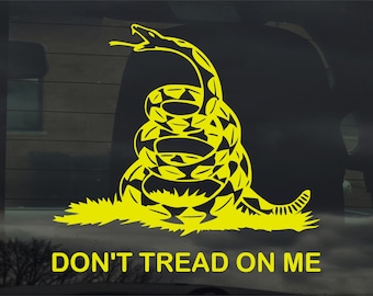 May include: Yellow coiled snake graphic with the text "DON'T TREAD ON ME". The snake is depicted with its tongue out, and the design is set against a dark background. The text is in a bold, sans-serif font.