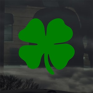 May include: A bright green four-leaf clover decal. The clover is a symbol of good luck and is often associated with St. Patrick's Day. The decal is likely designed for application on a car window or other smooth surface.