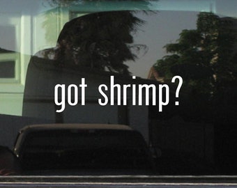 May include: A white vinyl sticker with the text "got shrimp?" on a black car window.