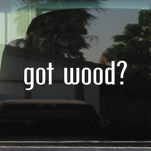 May include: A white vinyl decal with the text "got wood?" on a black car window.