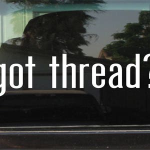 May include: White vinyl decal with the text "got thread?" on a black car window.