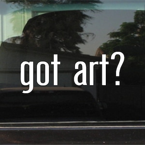 May include: White vinyl decal with the text "got art?" on a black car window.