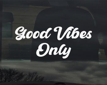 May include: White vinyl decal with the text "Good Vibes Only" in a retro, cursive font. The decal is on a black car window.