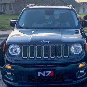 May include: A black Jeep Renegade with a silver grille and headlights. The car has a number plate that says "N7".