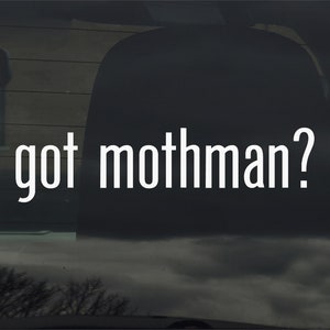 May include: A rear window car sticker with the text "got mothman?" in white letters on a black background.