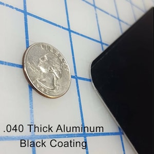May include: A close-up of a black metal sheet with a .040 thick aluminum black coating. A US quarter is shown for scale.
