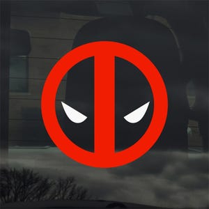 May include: A red and white decal featuring the Deadpool logo. The logo is a stylized face with white eyes inside a red circle with a vertical line through the center. The decal is likely for a car window or similar surface.