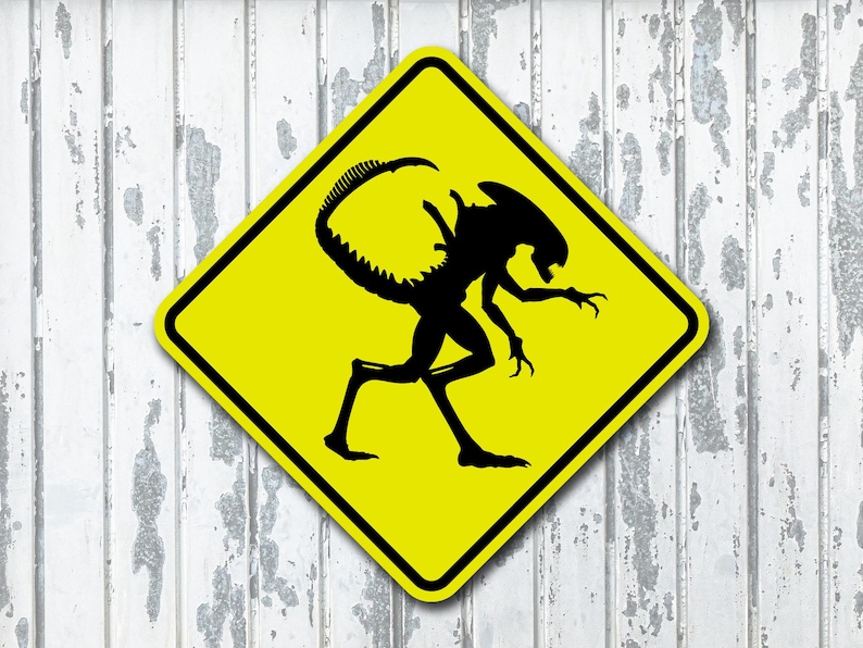 Placa de metal amarela com a inscrição "Aliens Xenomorph Crossing" (Atravessando Aliens Xenomorphs)
