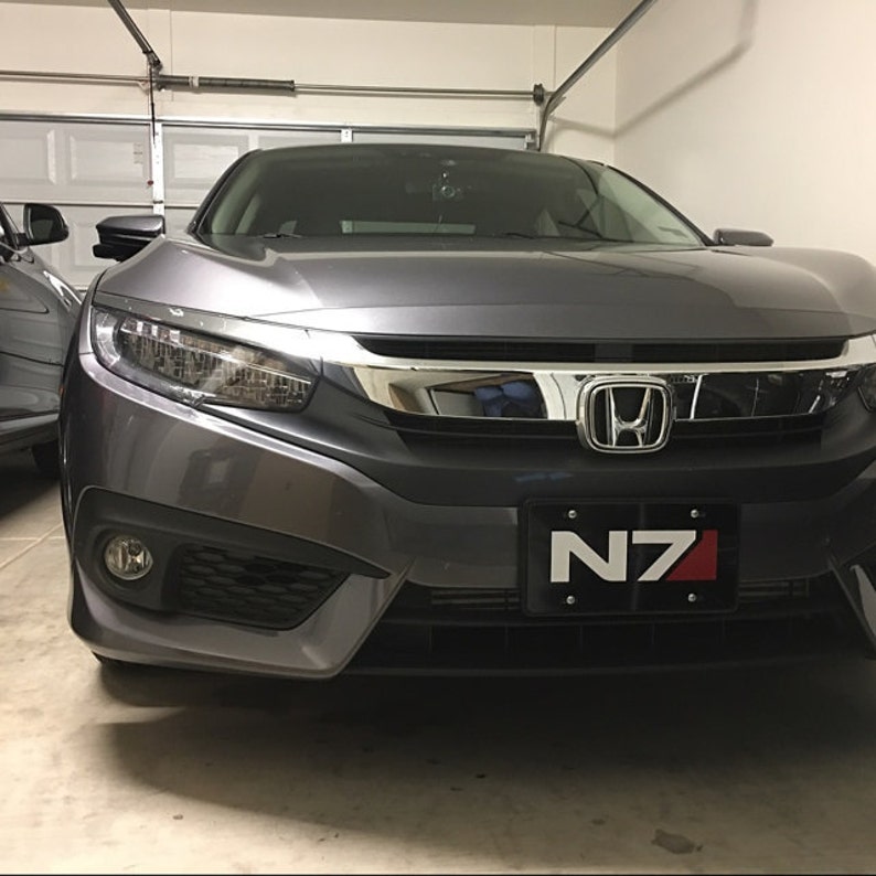 May include: A grey Honda Civic with a black number plate that reads "N7" in white lettering. The car is parked in a garage.