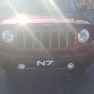 May include: A red Jeep Patriot with a black front grille and a number plate that reads "N7".