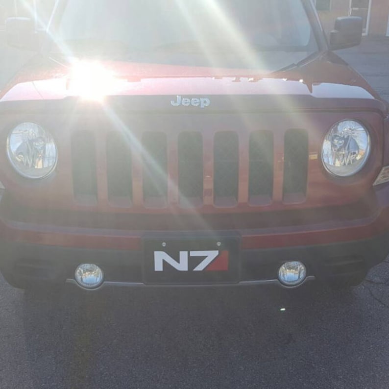 May include: A red Jeep Patriot with a black front grille and a number plate that reads "N7".