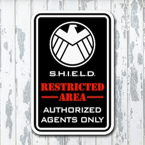 May include: Black and white sign with the S.H.I.E.L.D. logo. The sign reads "Restricted Area - Authorized Agents Only".