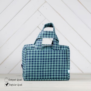 May include: A green and blue checkered tote bag with a double handle. The bag is made of fabric and has a zipper closure.