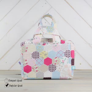 May include: A patchwork fabric tote bag with a pink, blue, and yellow geometric pattern. The bag has two handles and a square shape.
