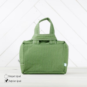 May include: A green fabric tote bag with a white chevron pattern. The bag has a single top handle and a zipper closure.