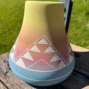 May include: A yellow, pink, and blue ceramic vase with a geometric pattern. The vase is hand-painted and has a unique, Southwestern style.
