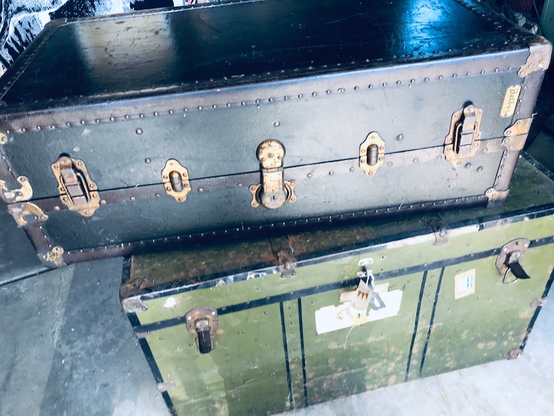 May include: Two vintage green metal suitcases with brass hardware and rivets. The top suitcase has a label that says "Sterling".