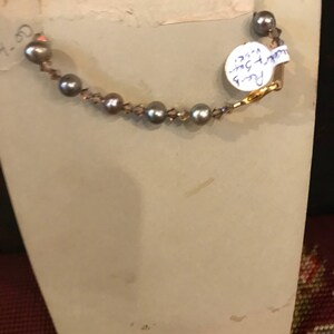 May include: A vintage photo with a pearl necklace on the back. The photo has a white background and a handwritten note on the back that says "Pearl 9-1/2" inches.