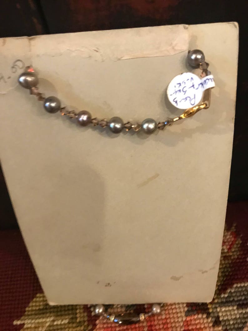 May include: A vintage photo with a pearl necklace on the back. The photo has a white background and a handwritten note on the back that says "Pearl 9-1/2" inches.