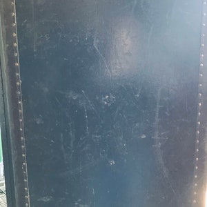 May include: A dark blue vintage suitcase with metal rivets around the edges.