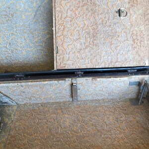 May include: The inside of a vintage suitcase with a brown floral patterned lining. The suitcase has a metal latch and hinges.