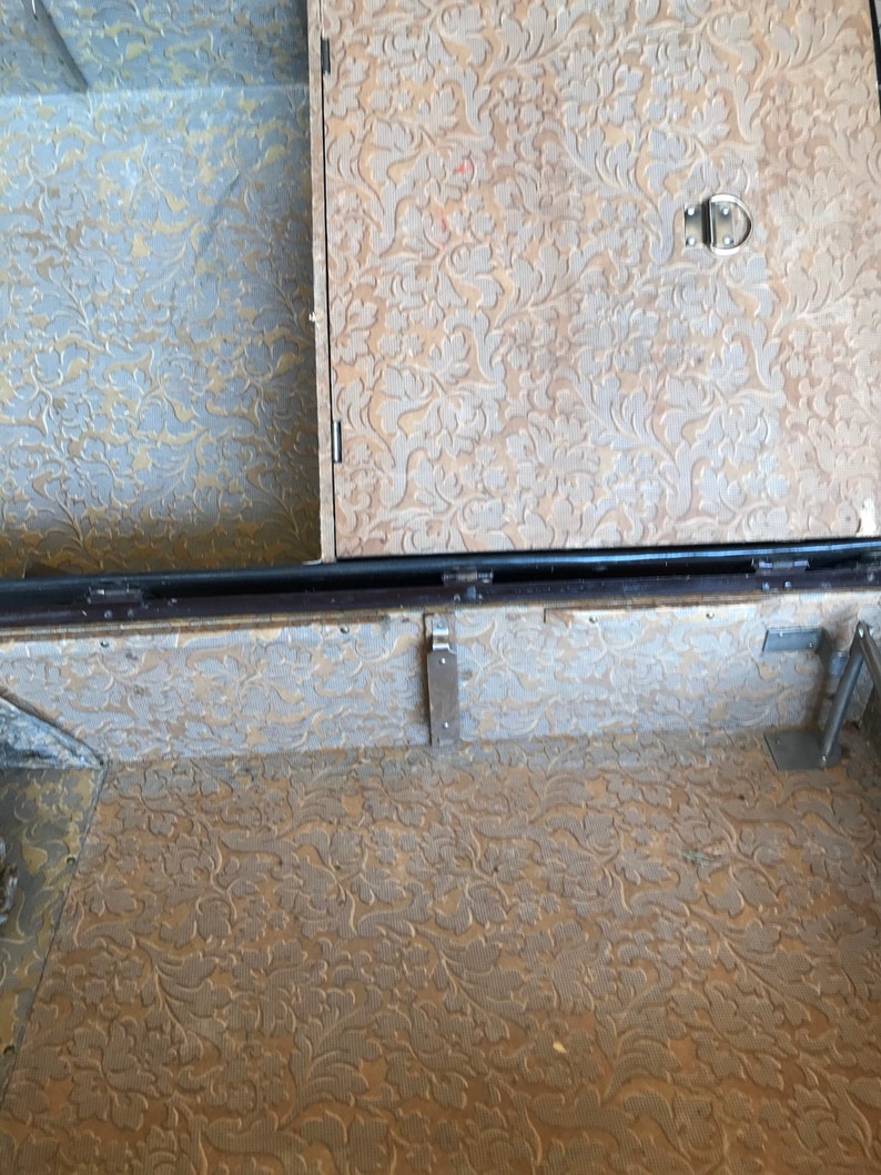 May include: The inside of a vintage suitcase with a brown floral patterned lining. The suitcase has a metal latch and hinges.