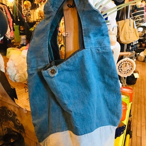 May include: A blue denim tote bag with a white denim bottom. The bag has a single strap and a button closure.