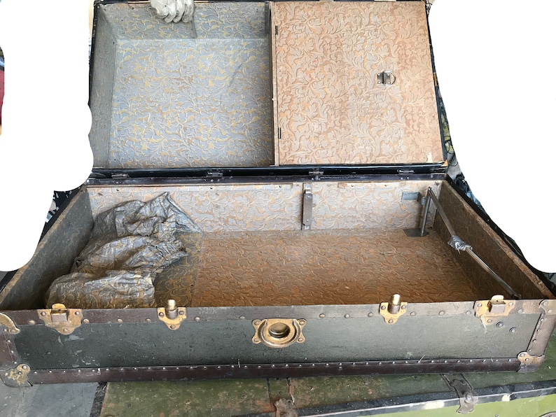 May include: A vintage green travel trunk with brass hardware and a patterned lining. The trunk is open and empty, revealing the interior lining.