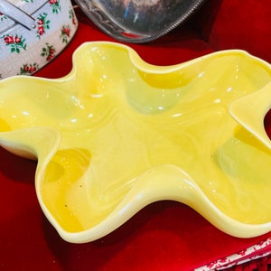 May include: A yellow ceramic serving dish with a unique, organic shape. The dish has four sections and is perfect for serving snacks or appetizers.