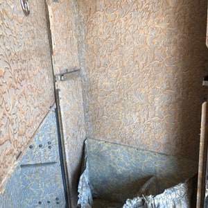May include: The inside of a vintage suitcase with a floral patterned lining. The suitcase is open and the lining is visible. There is a white cloth inside the suitcase.