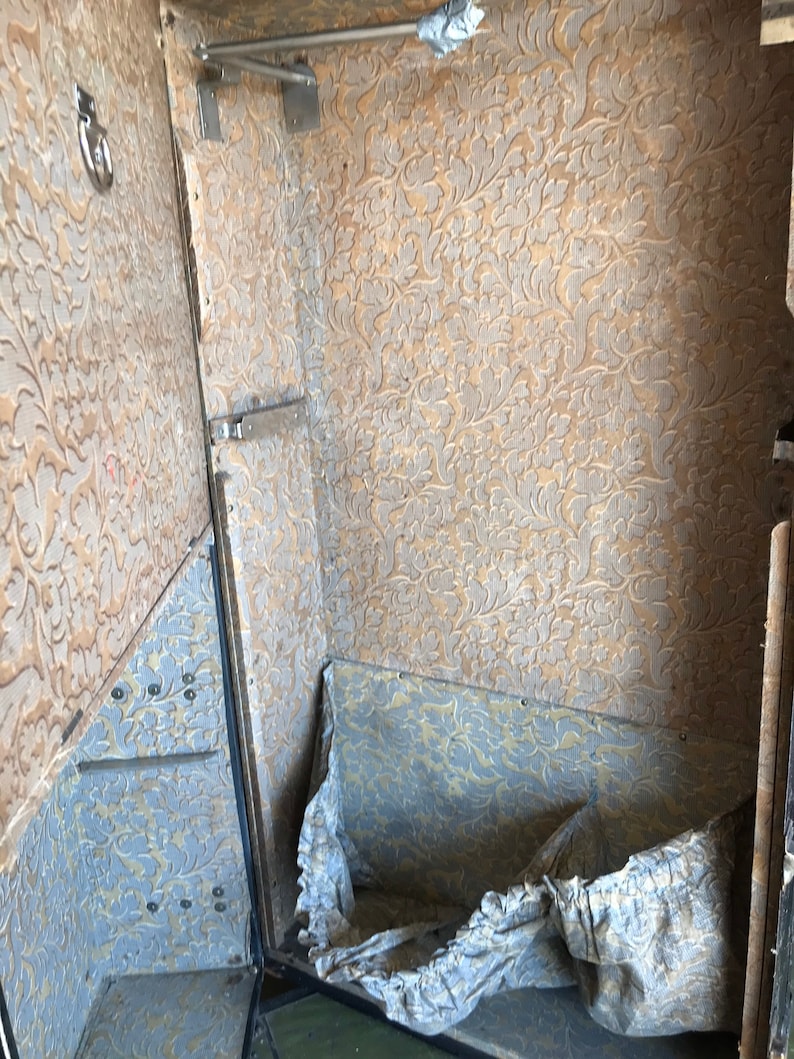 May include: The inside of a vintage suitcase with a floral patterned lining. The suitcase is open and the lining is visible. There is a white cloth inside the suitcase.