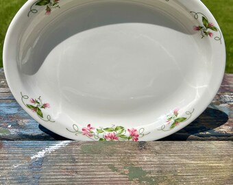 May include: A white oval ceramic baking dish with a floral design. The dish has a pink and green floral pattern around the rim.