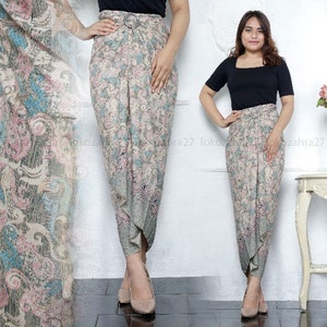 May include: Two women wearing long, flowing skirts with a floral pattern. The skirts are tied at the waist and have a draped look. The women are standing on a white background.