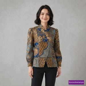 May include: A long-sleeved blouse featuring a patchwork design of blue and brown batik patterns with intricate floral and geometric motifs, a mandarin collar, and a button-down front, paired with solid black trousers.