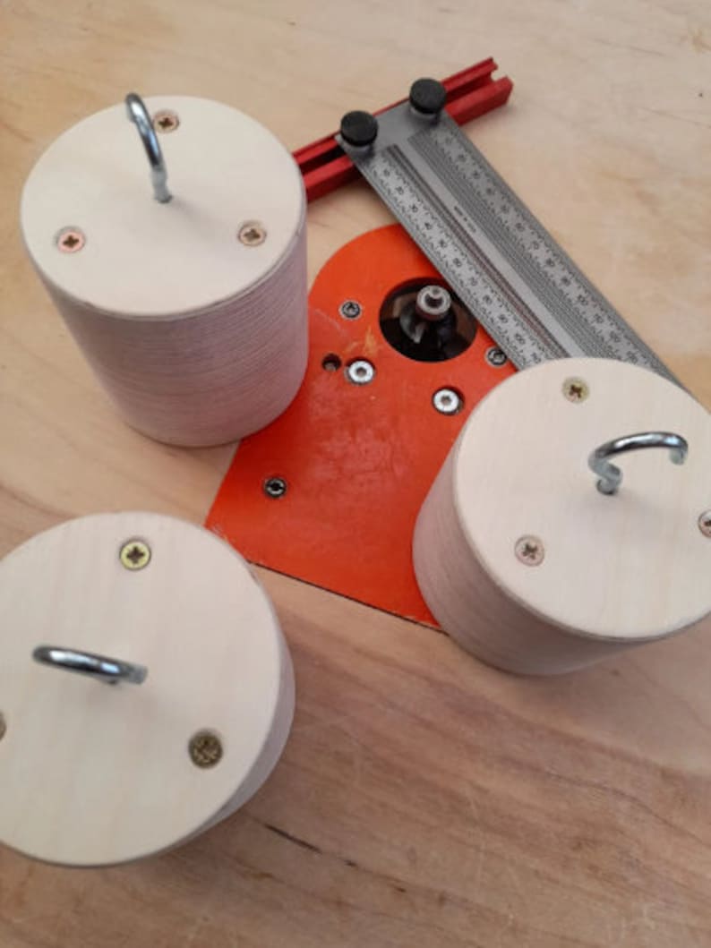 May include: Three wooden circles with hooks attached to the top. The circles are made of light wood and have a natural finish. The hooks are made of metal and are silver in color. The circles are sitting on a wooden surface.