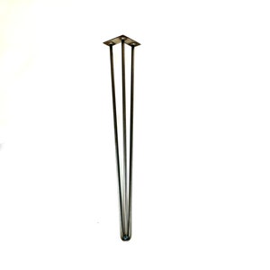 May include: A silver metal hairpin leg with three prongs. The leg is designed to support furniture.