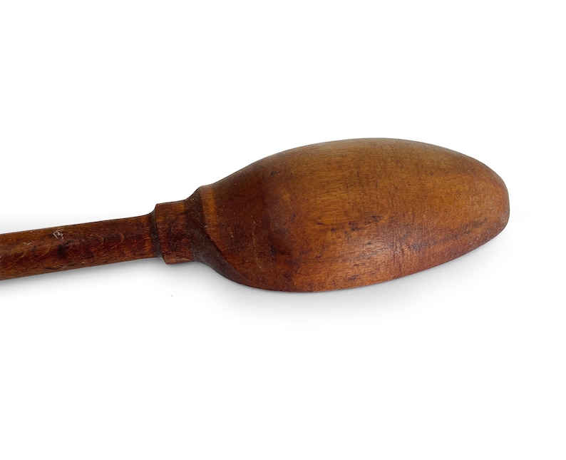 May include: A wooden spoon with a long handle and a rounded bowl. The spoon is made of dark brown wood and has a smooth, polished finish.