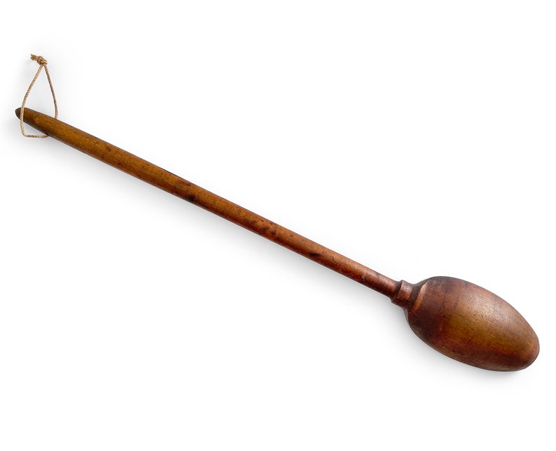 May include: A long, wooden spoon with a rounded, oval-shaped bowl. The spoon has a brown color and a string tied to the handle.