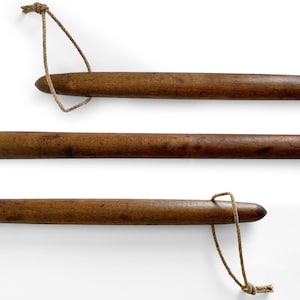 May include: Three wooden dowels with a knotted rope attached to each end. The dowels are brown and have a smooth finish.