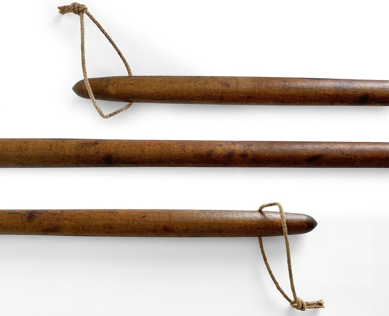 May include: Three wooden dowels with a knotted rope attached to each end. The dowels are brown and have a smooth finish.