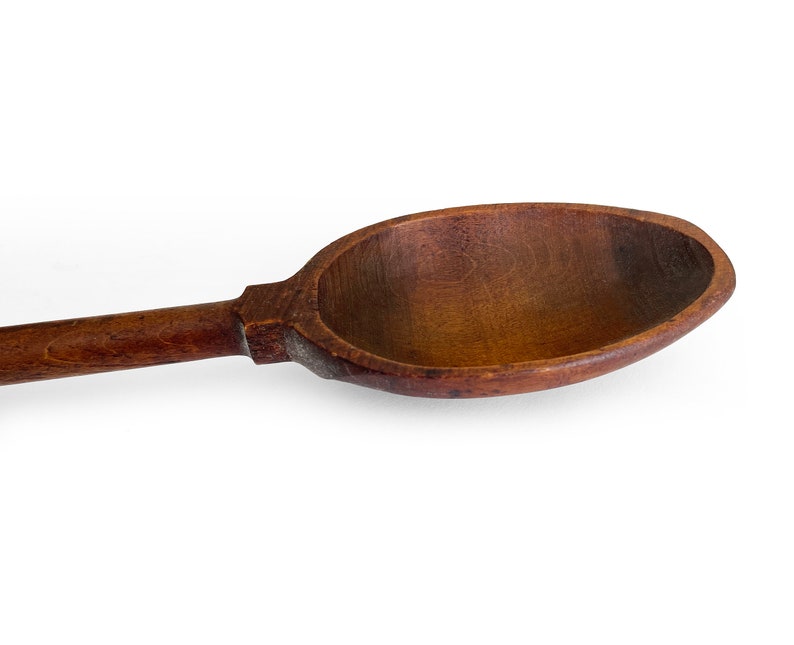 May include: A large, wooden spoon with a long handle. The spoon is made of dark brown wood and has a smooth, rounded bowl.