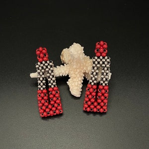 May include: A pair of red and silver beaded earrings. The earrings are shaped like a rectangle and have a geometric design.
