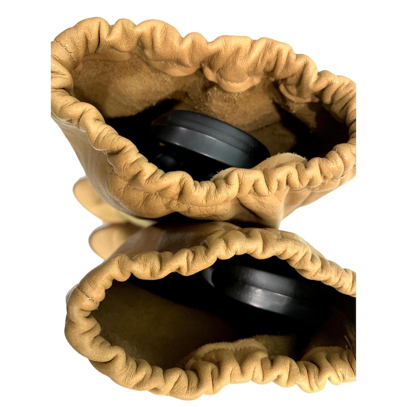 May include: Two tan leather gloves with a drawstring closure. The gloves are open, revealing a black object inside each one. The leather has a slightly wrinkled texture. The background is white.